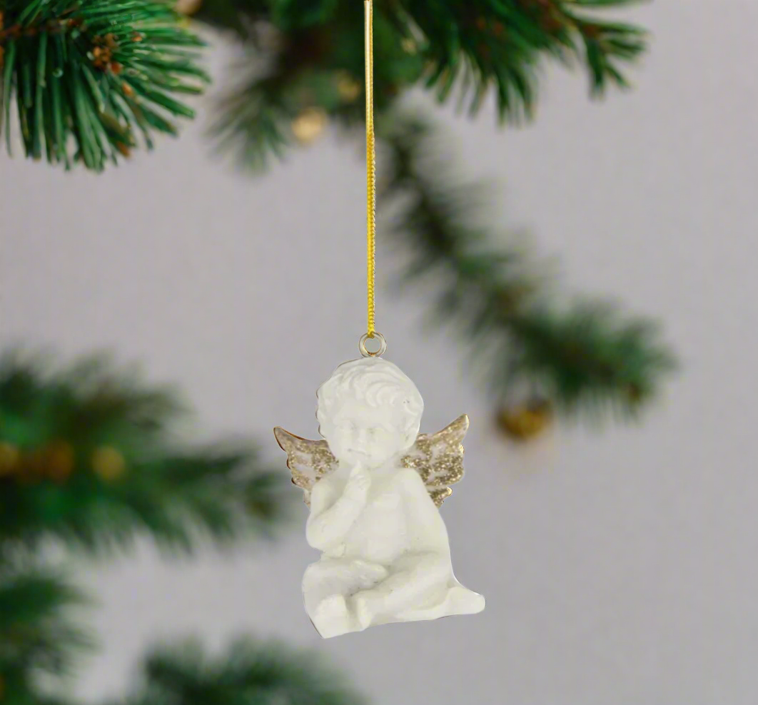 White angel ornament with gold wings on a fir branch