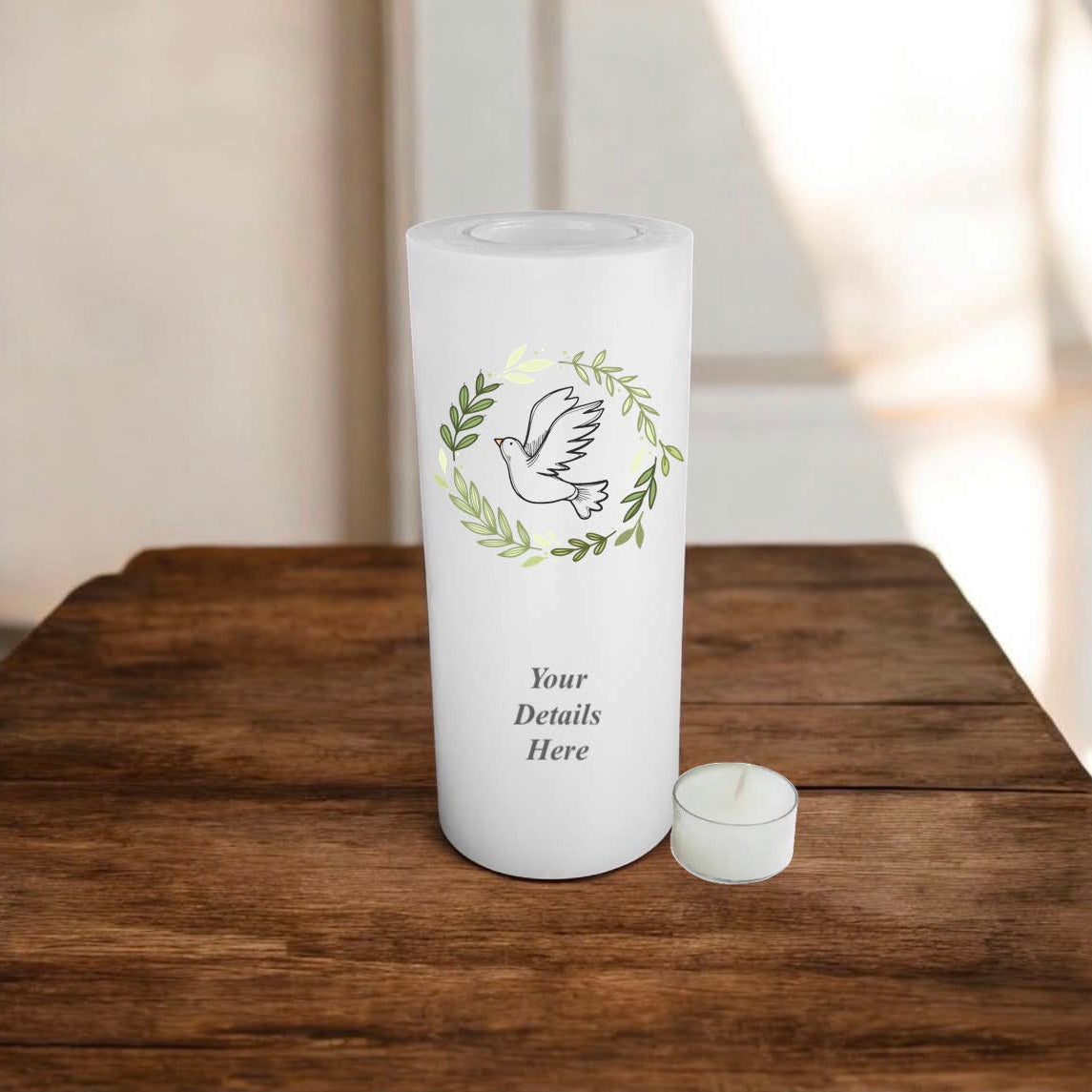 White candle with a bird in wreath design on a wooden surface