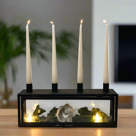 Candle holder with four candles and a small angel figure inside on a wooden table