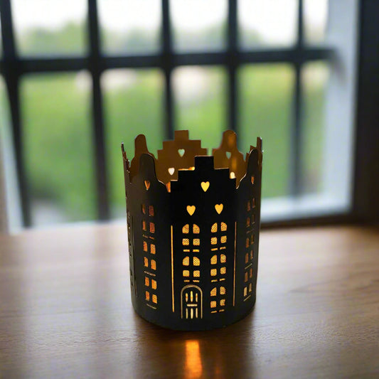 Decorative black candle holder with cut-out patterns on a wooden surface 