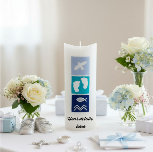 Decorative candle with baby symbols on a table with flowers and baby shoes.