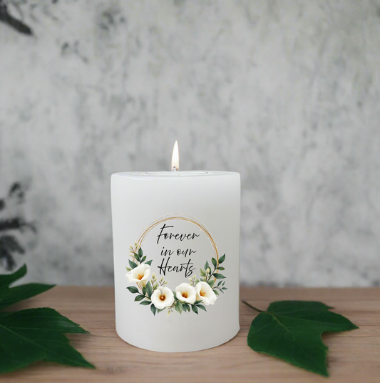 Candle with floral design and text on a wooden surface with leaves.