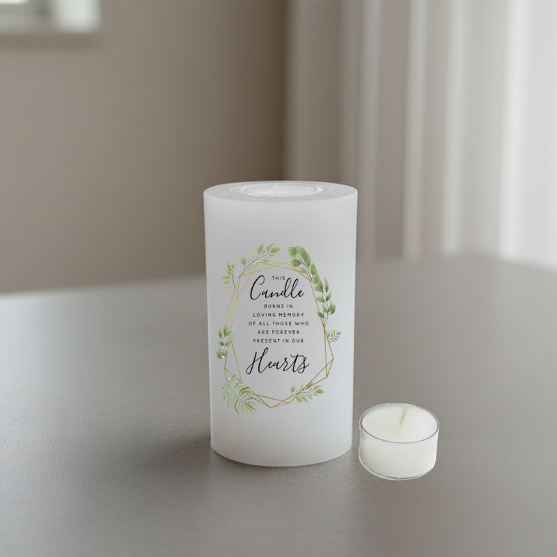 A white memorial candle with a printed green floral wreath and gold geometric border.