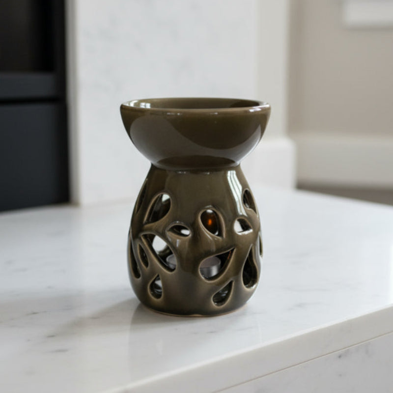 Brown ceramic oil burner with decorative holes on a white background