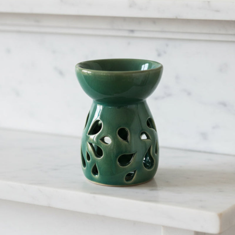 Green ceramic oil burner on a marble surface