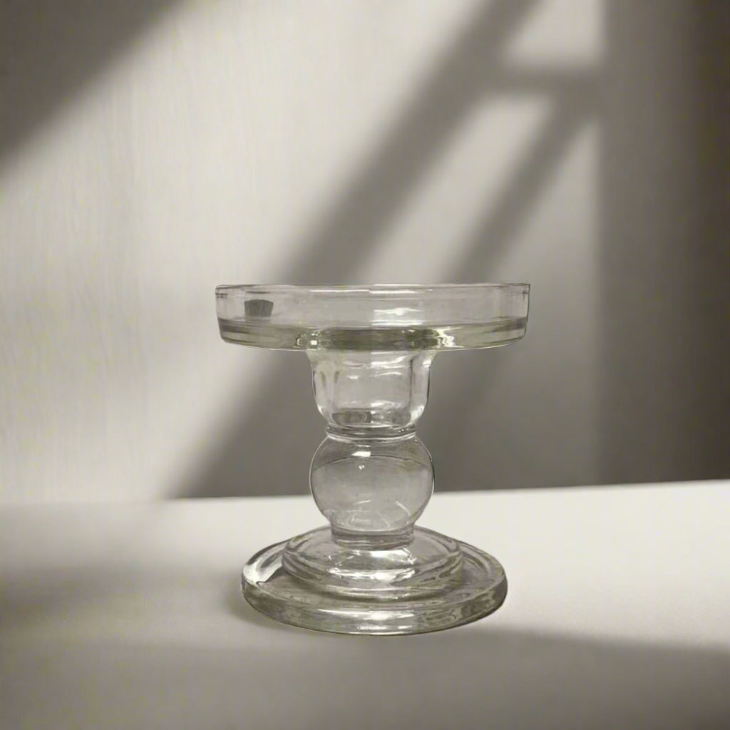 Clear glass candle holder on a wooden surface with a rustic background
