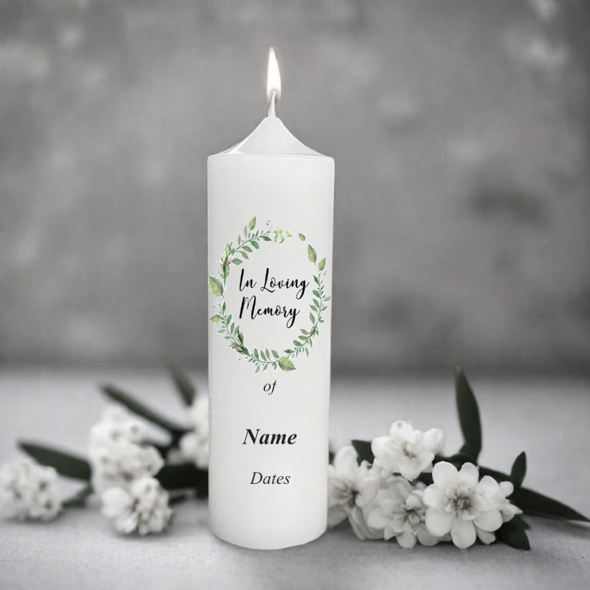 White memory candle with 'In Loving Memory' text and floral design, surrounded by white flowers on a grey background.