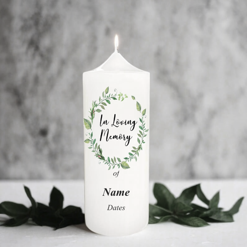 White memory candle with greenery design and text on a grey background