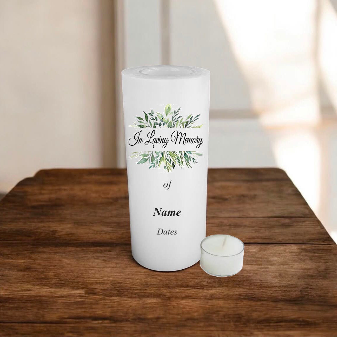 A white memorial candle with a green leaf design and a message