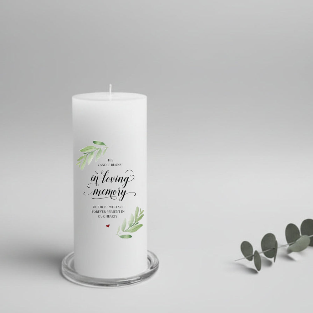 White memory candle with text and green leaves design on a gray background