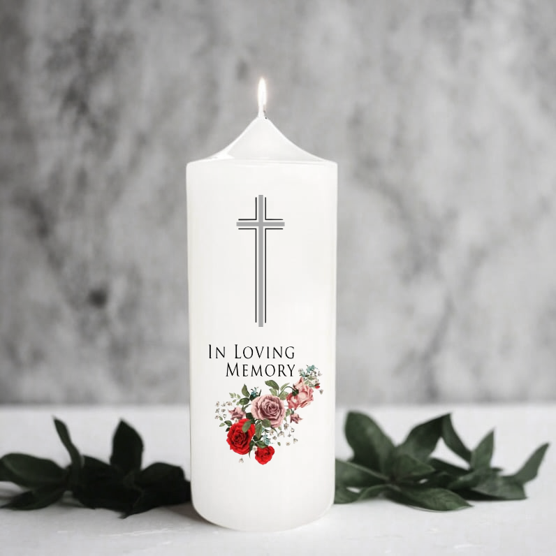 White memory candle with cross and floral design on a gray background