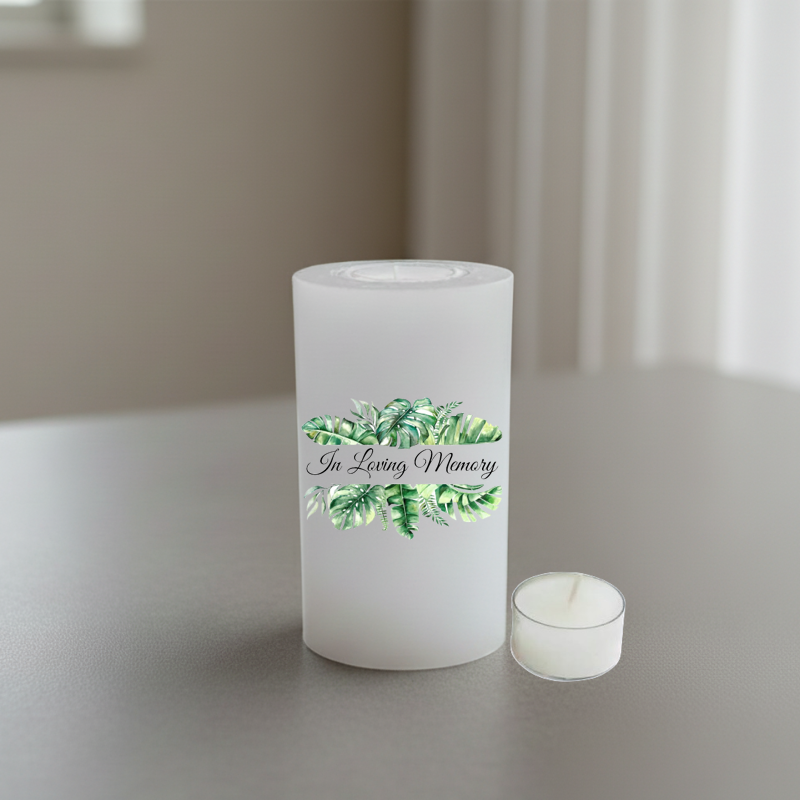 White memory candle printed with green leaves and text