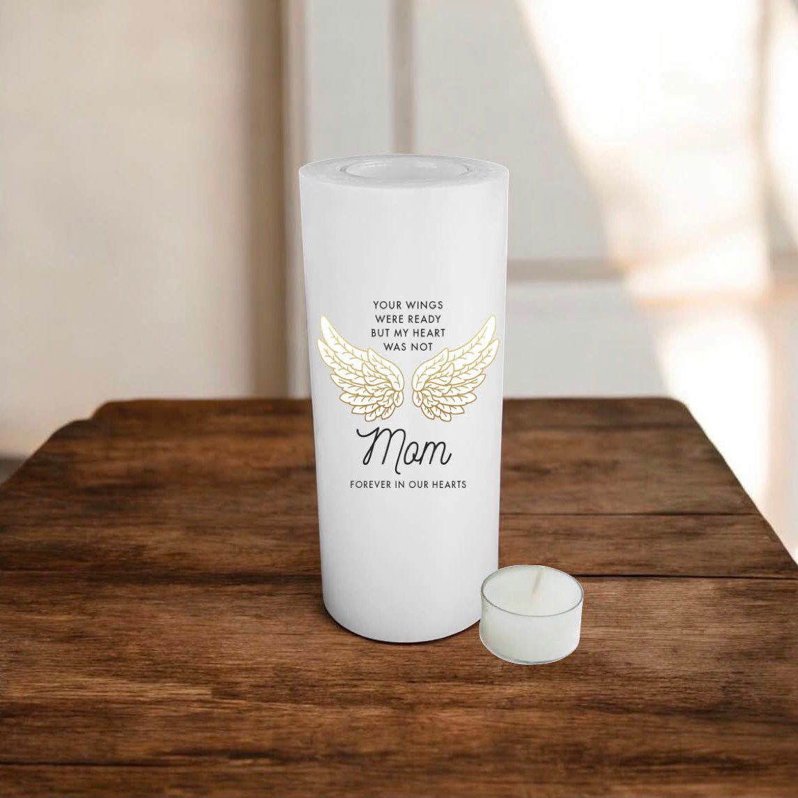 White candle of a size 8x19cm, printed with wings and text for mom, placed on a wooden surface