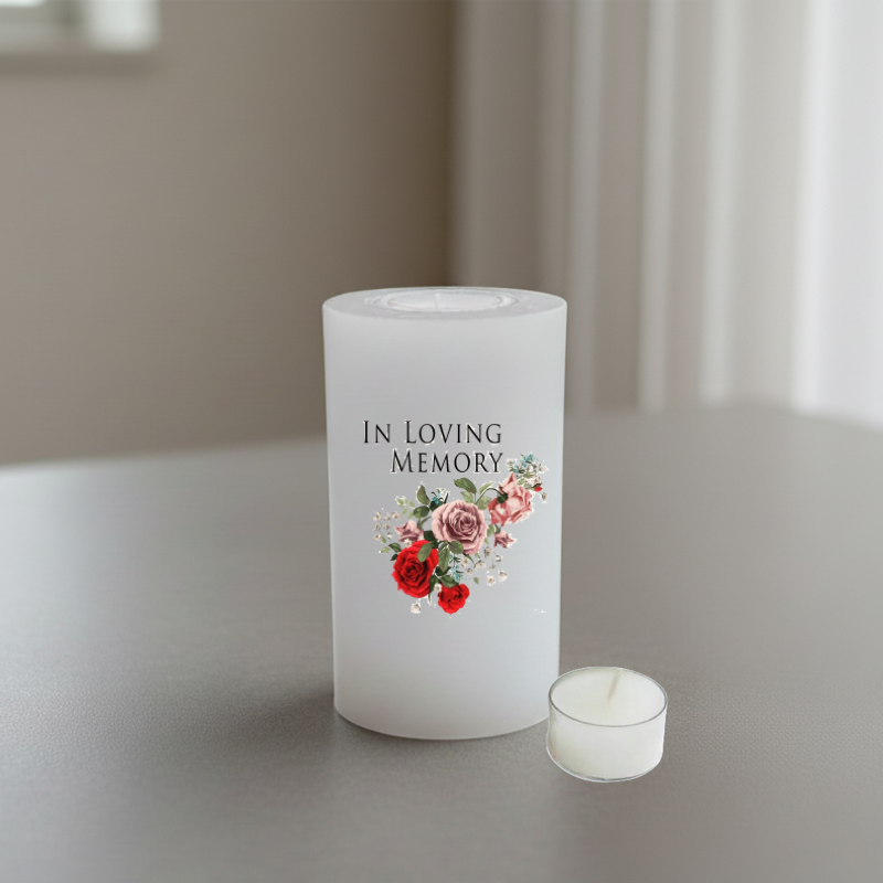 A white candle printed with the words "IN LOVING MEMORY" above a small floral bouquet in red, pink, and green tones.