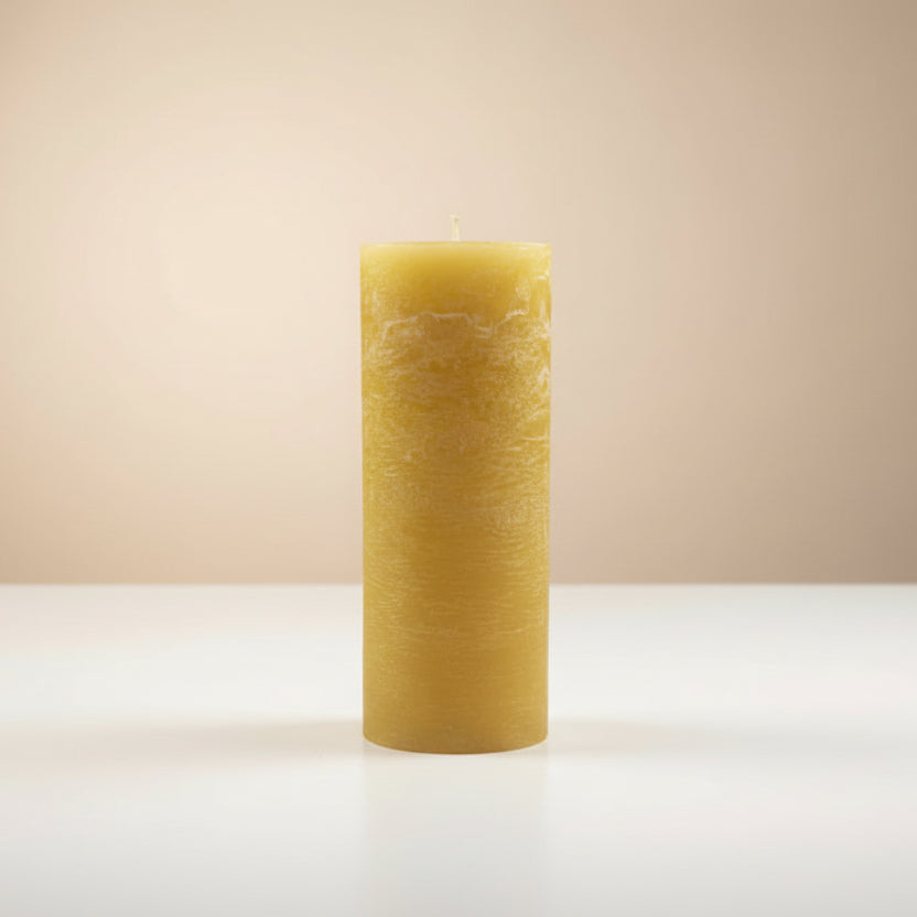 Textured mustard-yellow candle on a white surface with a beige background