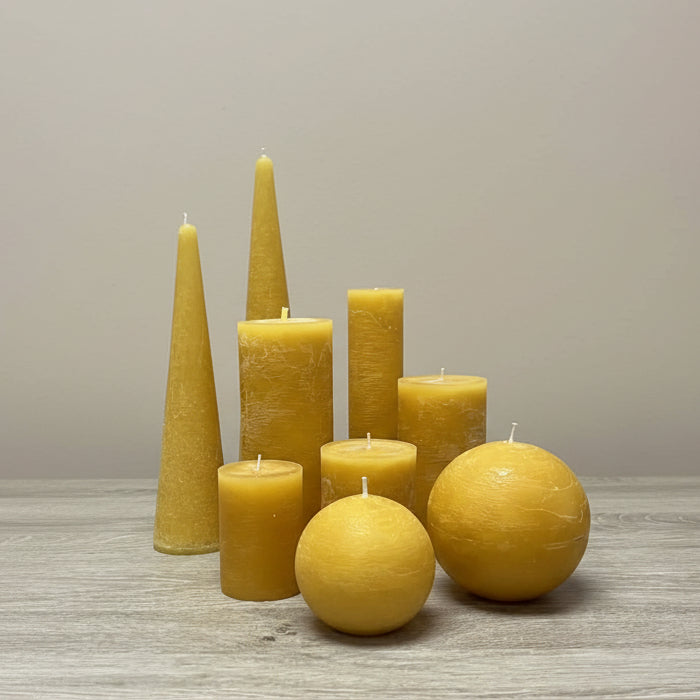 Mustard rustic candles of various shapes on a table 