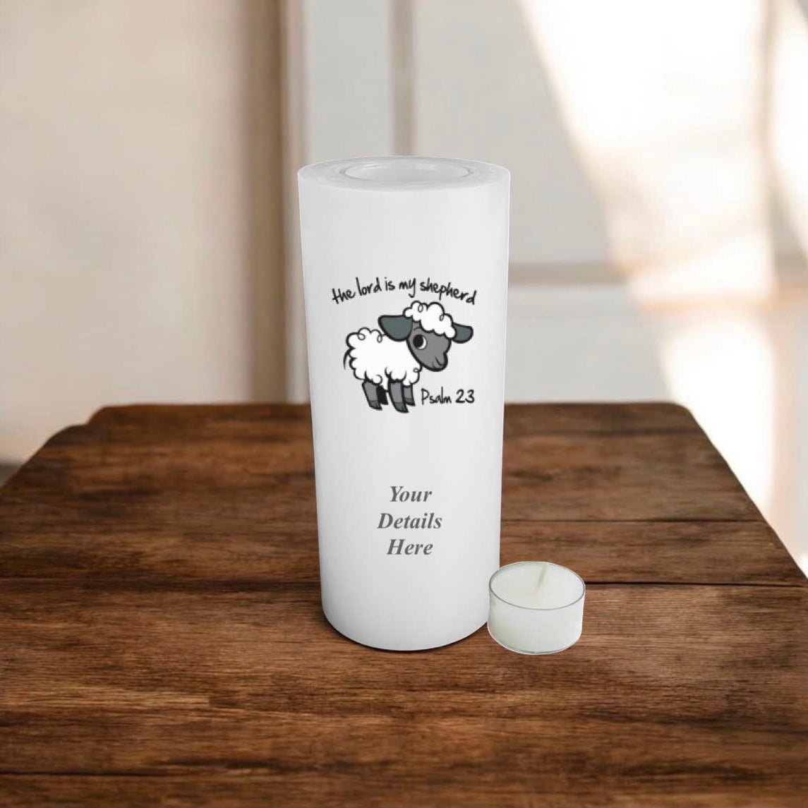 A white candle with religious picture and verse Psalm 23, placed on a wooden surface