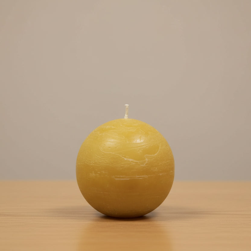 mustard ball candle on a counter and a neutral background