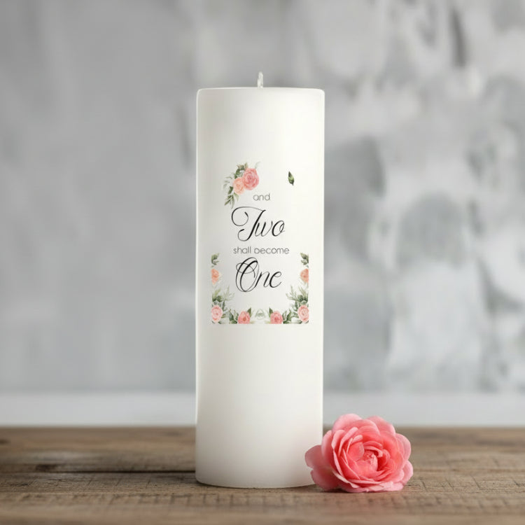 White wedding candle with floral design and text in a blurred indoor setting
