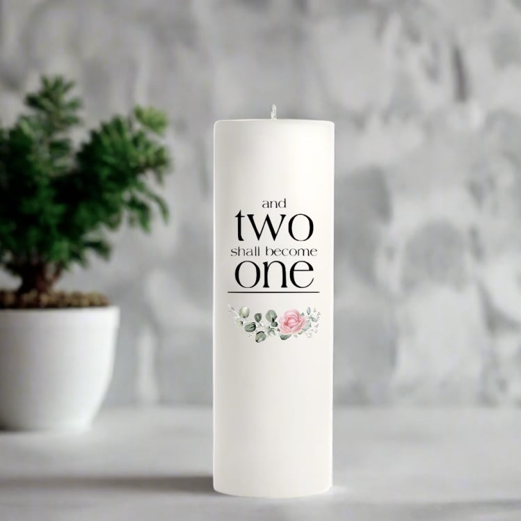 White wedding candle with text and floral design in a blurred indoor setting