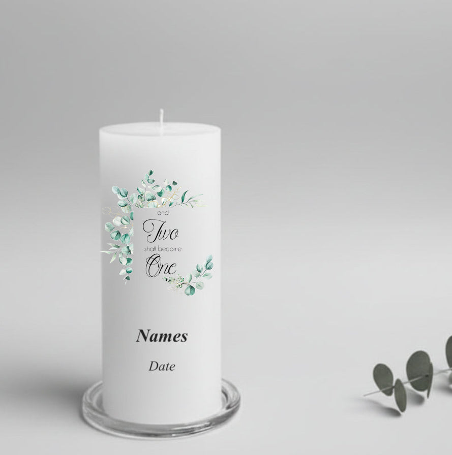 A white candle printed with  green leaves and the text 'and Two shall become One' plus 'Names' and 'Date'. 