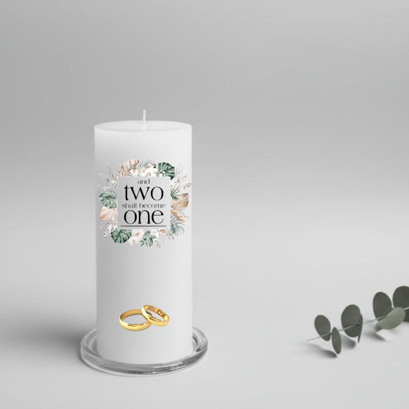 White wedding candle with floral design and text, gold rings on a gray background