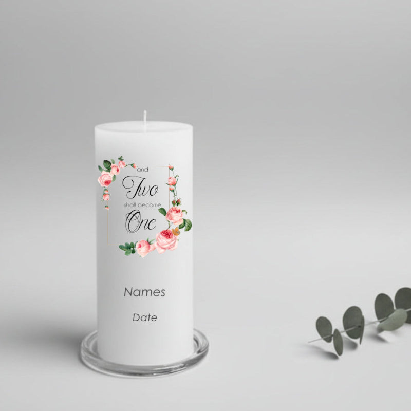 A white cylindrical candle on a light grey background, printed with a pink floral design and the union words 