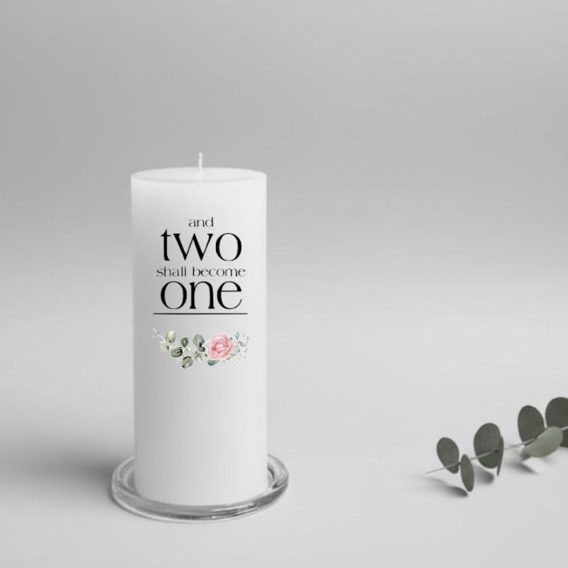 White wedding candle with text and floral design in a clear holder on a light gray background